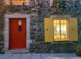 Stone building exterior with red door and yellow window shudders
