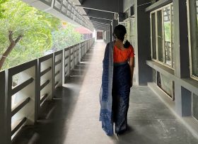 Sabrina walking down a hallway facing away from camera